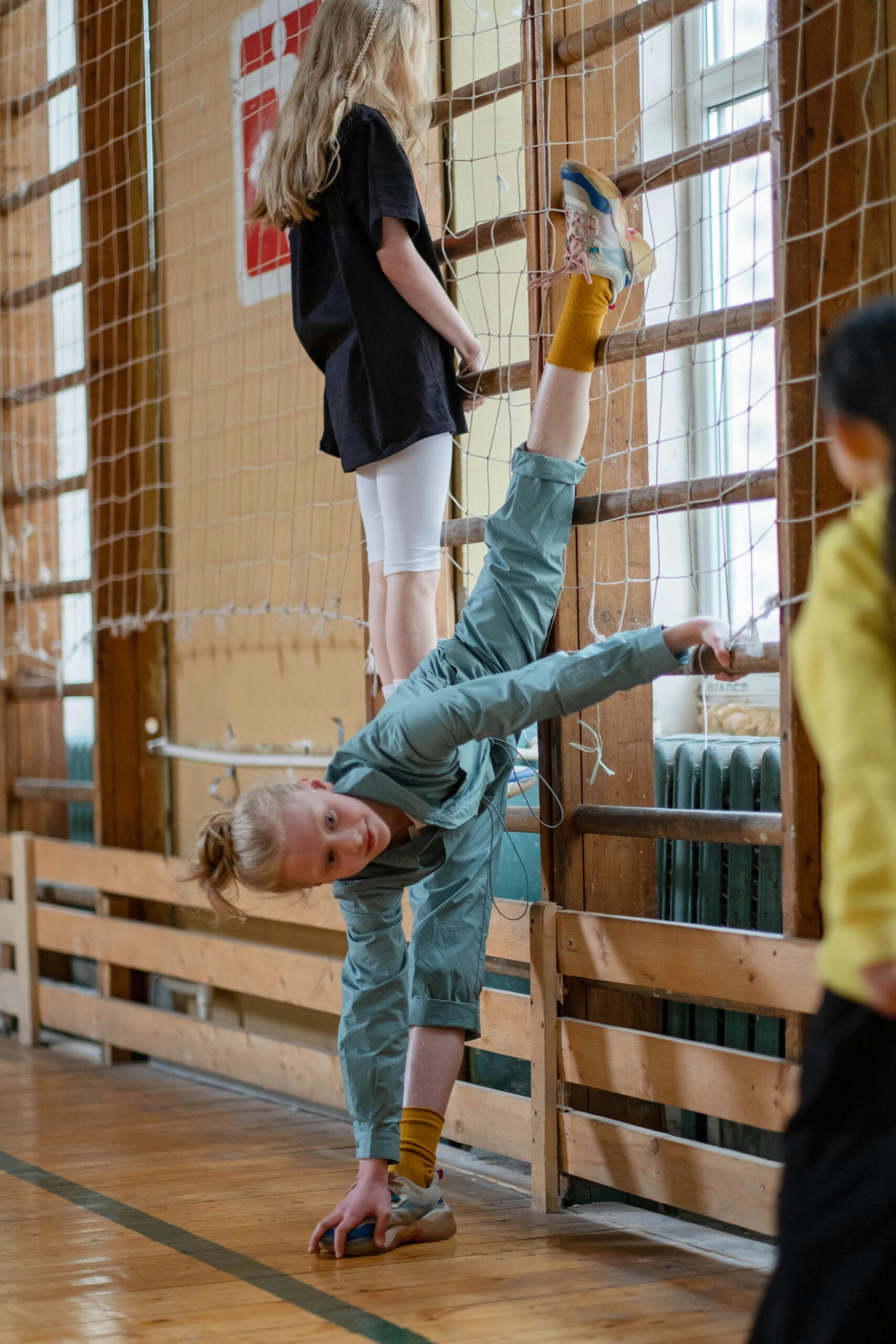 child-practicing -gymnastics -and-stretching -on-wooden-climbing -bars-in-a-school